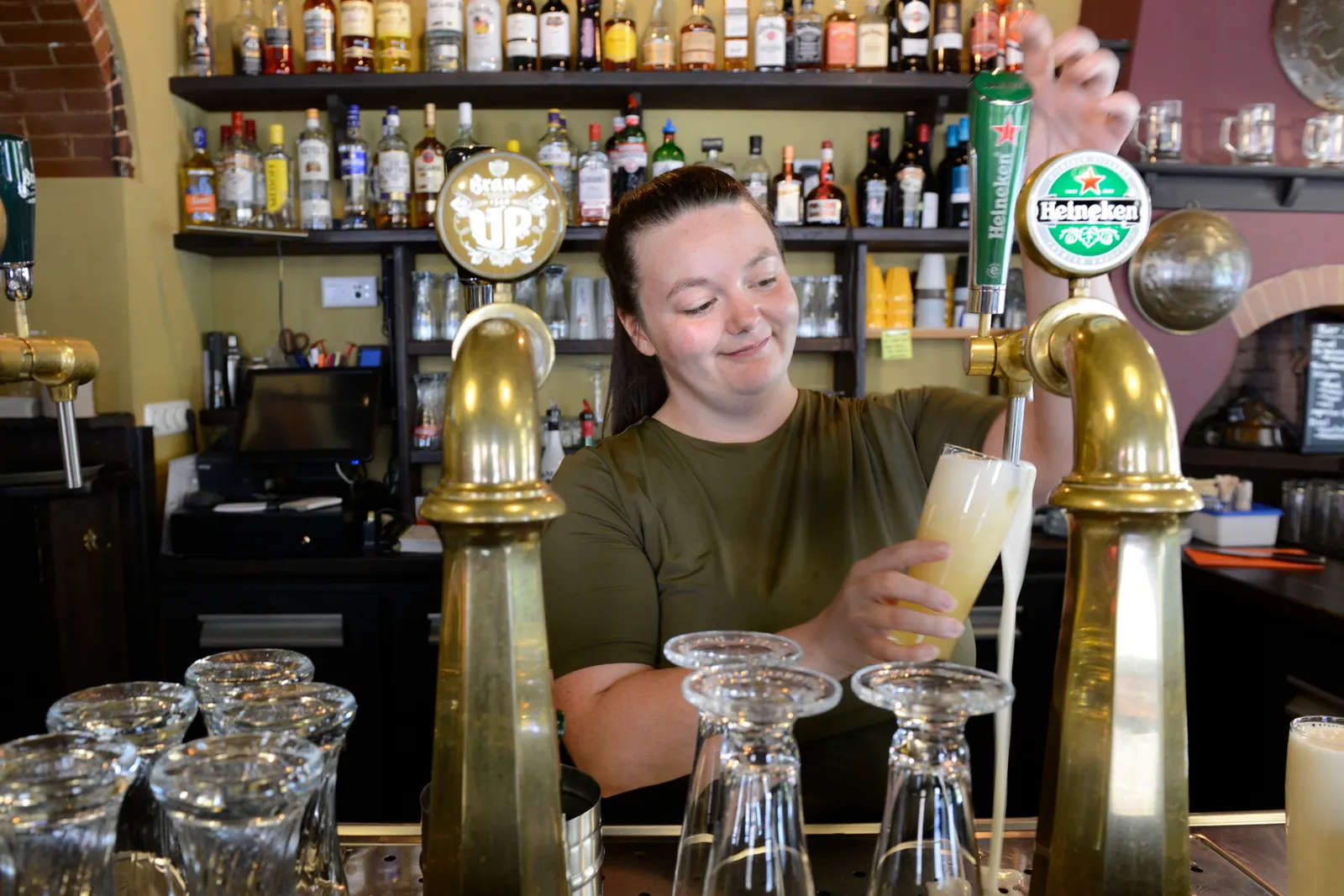 Nakita McFairlane tapt een biertje achter de koperen tapkranen van het Oranje Bierhuis