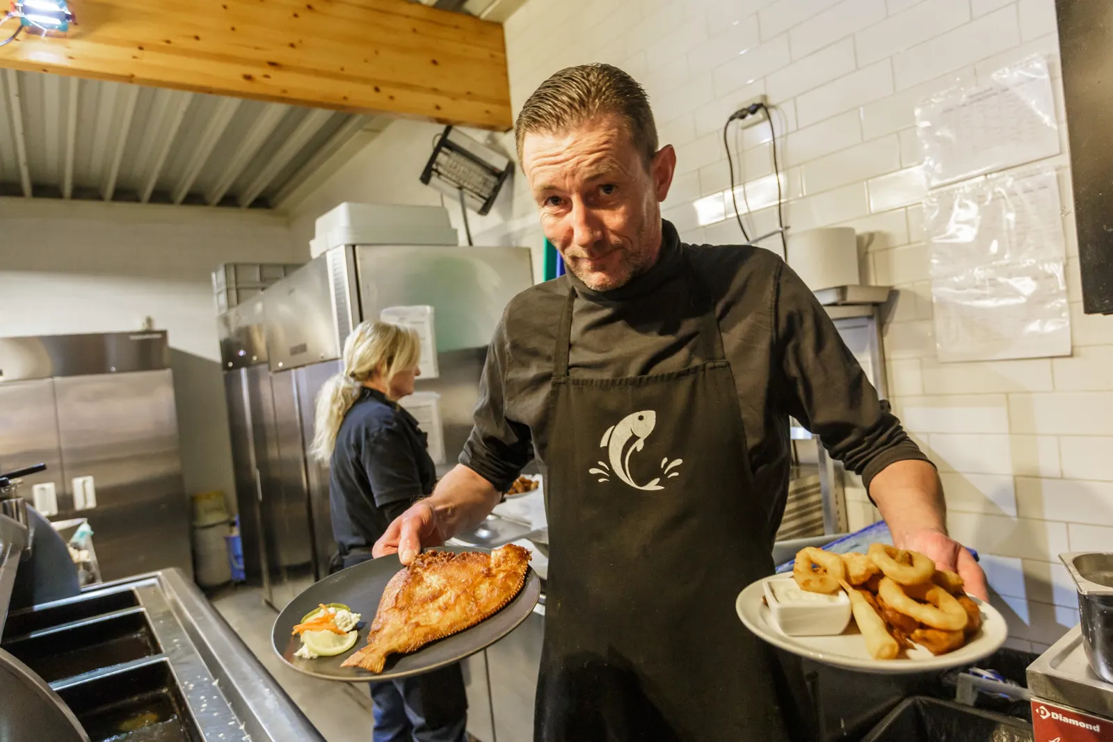 René Hofman in de keuken van De Gezonde Apotheek, met een gebakken platvis en een bord calamaris